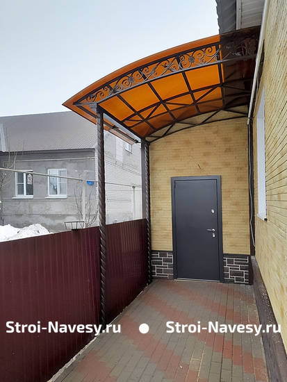 Навес из поликарбоната односкатный в виде крыльца к дому с декоративной ковкой Навес из поликарбоната односкатный в виде крыльца к дому с декоративной ковкой